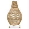 Natural base rattan table lamp casting warm patterned light in a modern bedroom setting