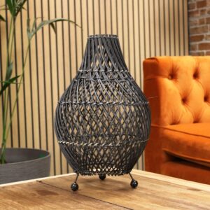Black base rattan table lamp casting warm patterned light in a modern bedroom setting