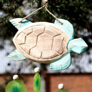 Handcrafted aqua turtle driftwood windchime with capiz shell drops hanging in a garden setting. Soft coastal windchime design bringing relaxed summer ambience.