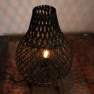Black base rattan table lamp casting warm patterned light in a modern bedroom setting