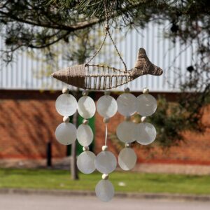 Handcrafted driftwood fish wind chime with cascading white capiz shells hanging indoors. A gentle coastal touch for relaxed living spaces.