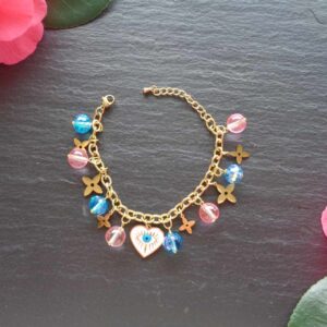 A playful and stylish bracelet featuring pink and blue glass beads, stainless steel over gold floral charms, and a heart evil eye centre piece for protection and good vibes. Handmade In Ireland with tracked An Post delivery.